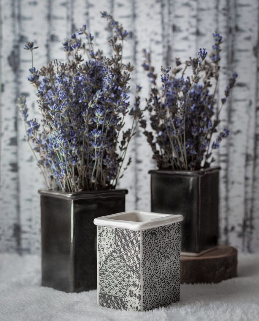 Three square vases with flowers in them on a table.