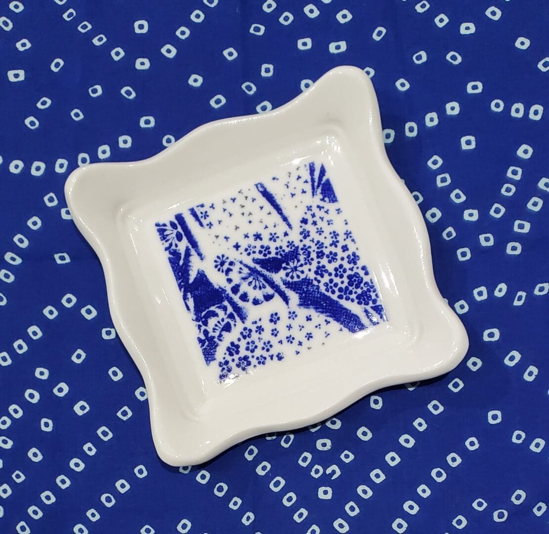 A square plate with blue and white design on it.