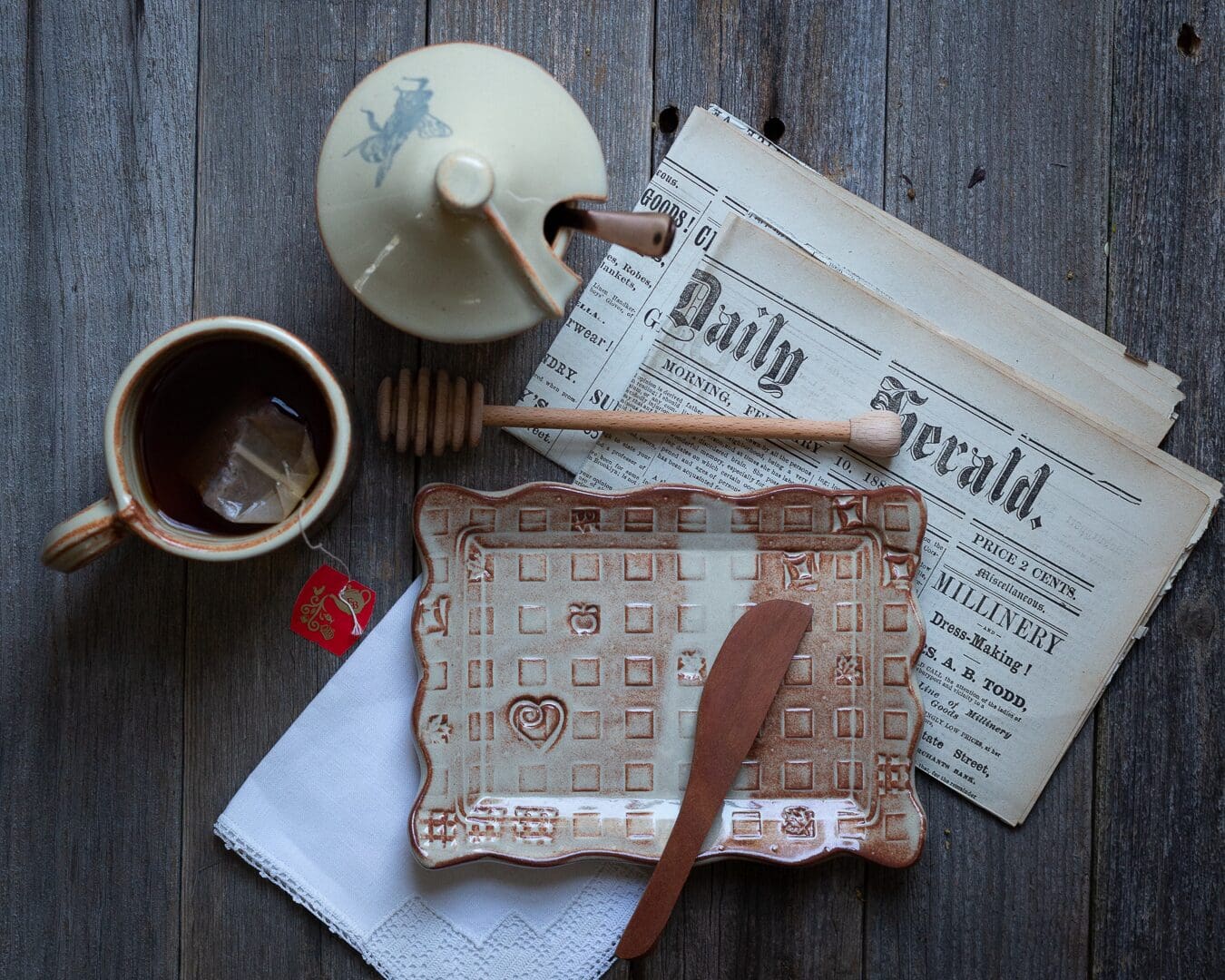 A wooden table topped with a newspaper and cup of coffee.